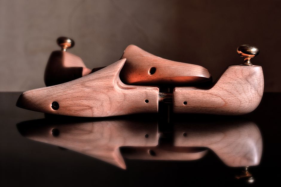 Close-up of polished wooden shoe trees reflecting on a glossy surface, showcasing craftsmanship.